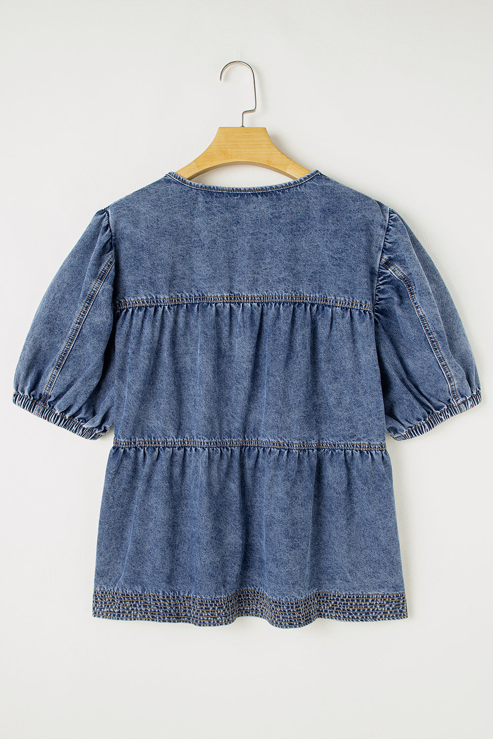 Blue denim dress on a hanger against a white background