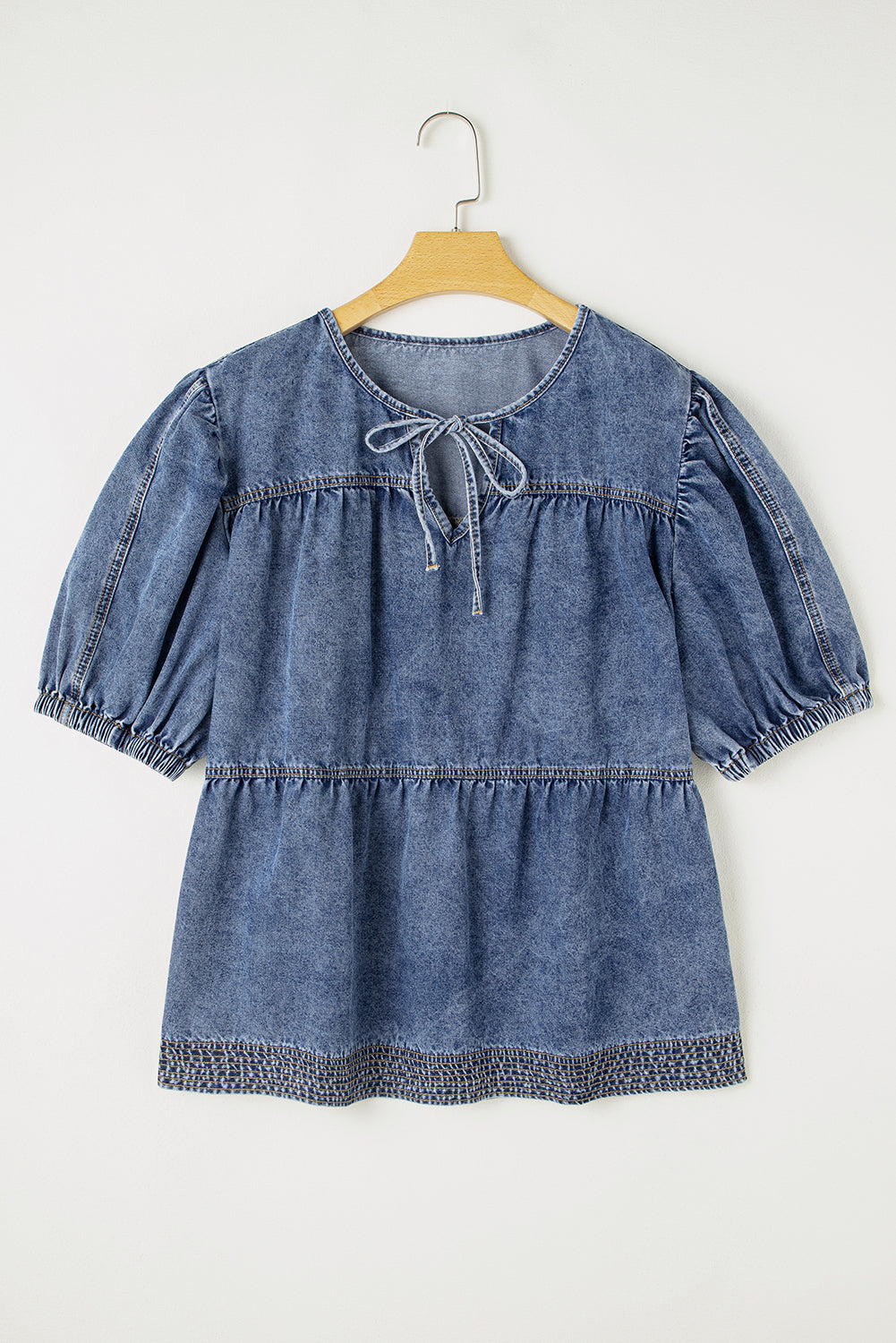 Denim dress on a hanger against a white background