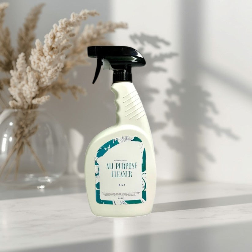 Doodlations All Purpose Cleaning Spray in Diva scent, a white bottle with a teal label, displayed in a clean kitchen.