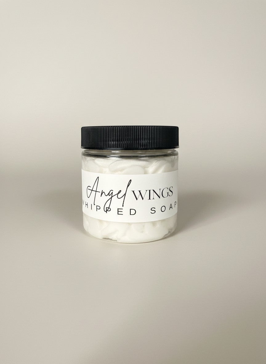 Doodlations Angel Wings whipped soap in a clear jar with a black lid. White, fluffy soap with a label.