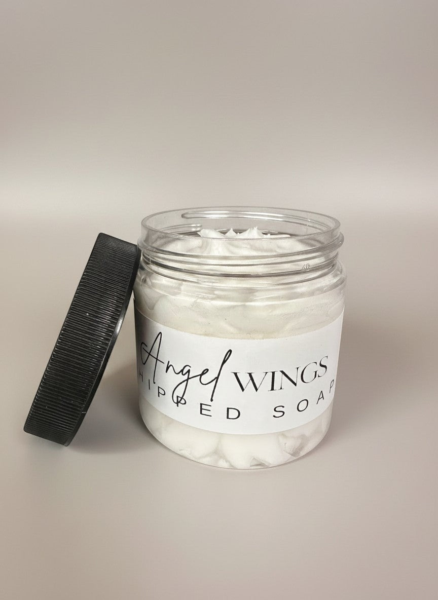 Doodlations Angel Wings whipped soap in a clear jar with lid off, featuring a fluffy white texture and a label with elegant script.