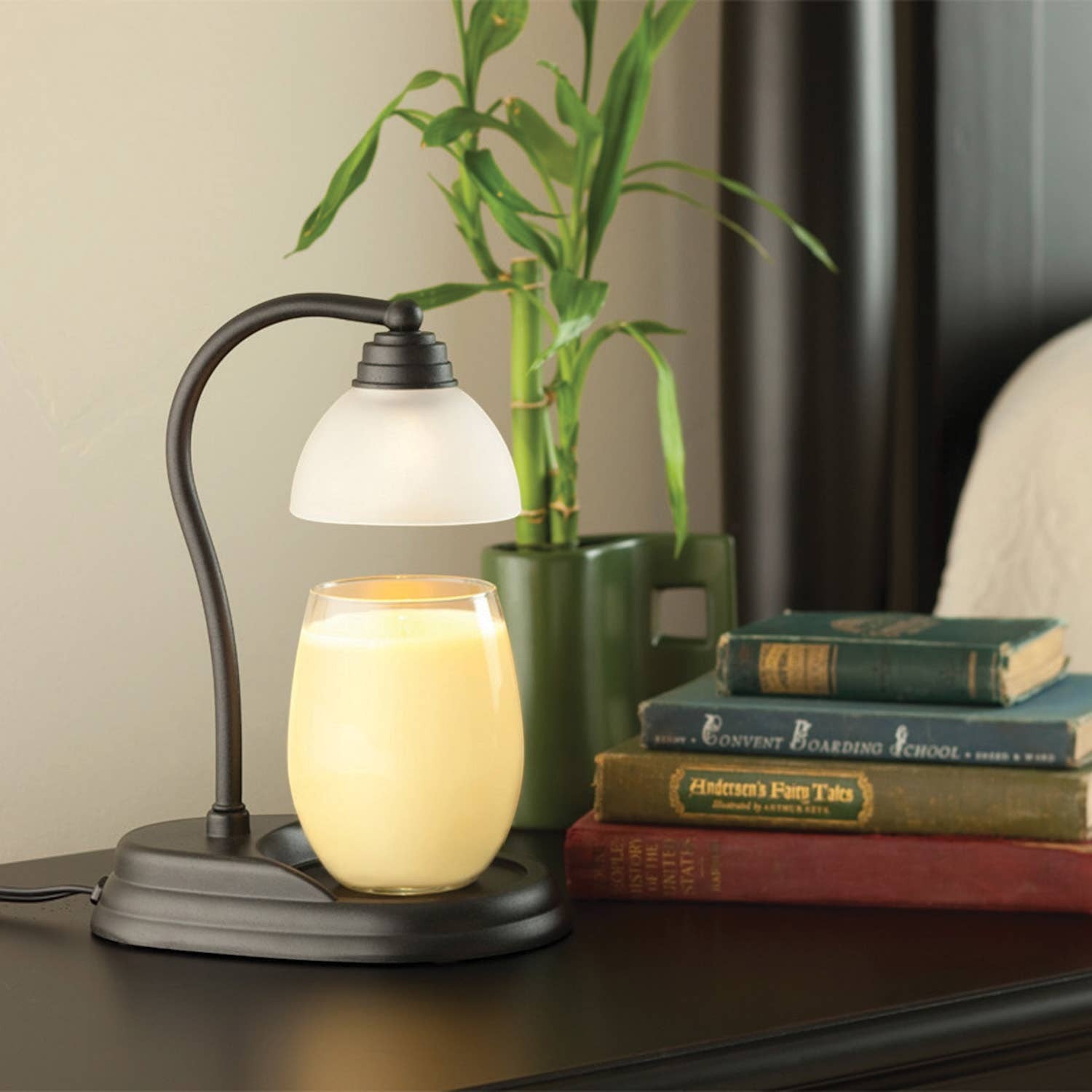 Doodlations Aurora black metal candle warmer lamp with frosted white shade, warming a yellow candle.