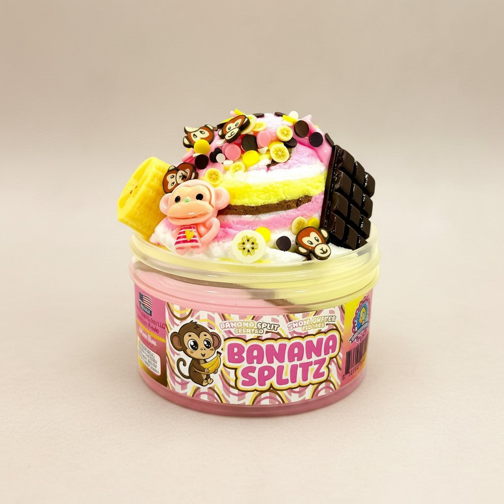 Doodlations Banana Splitz scented snow butter slime with pink, yellow, and brown layers, topped with banana, chocolate, and monkey charms.