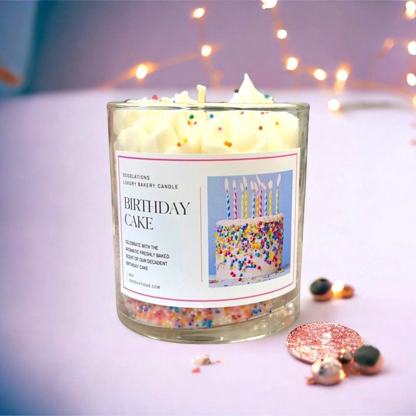 Doodlations Luxury Bakery Candle in Birthday Cake scent, topped with frosting and sprinkles.
