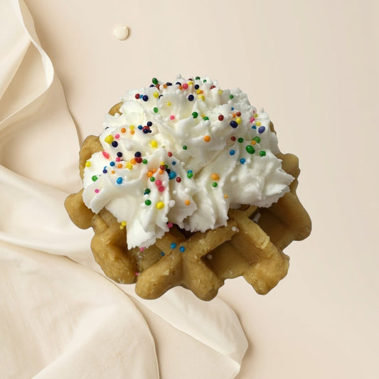 Doodlations Coffee Bar & Boutique Birthday Cake wax melt shaped like a waffle with whipped cream and rainbow sprinkles.