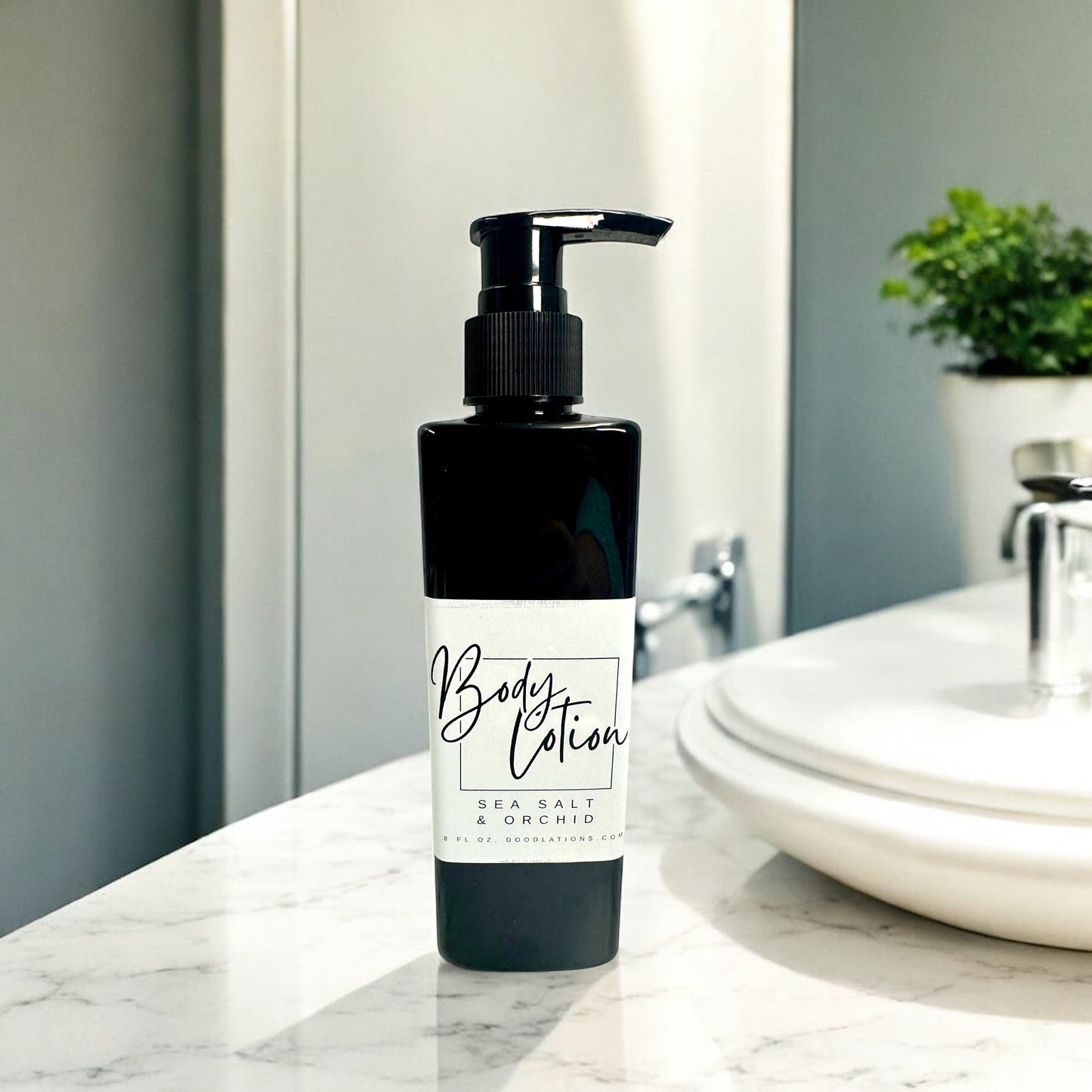 Doodlations Coffee Bar & Boutique black pump bottle of Sea Salt & Orchid body lotion, 8oz, on a marble countertop.
