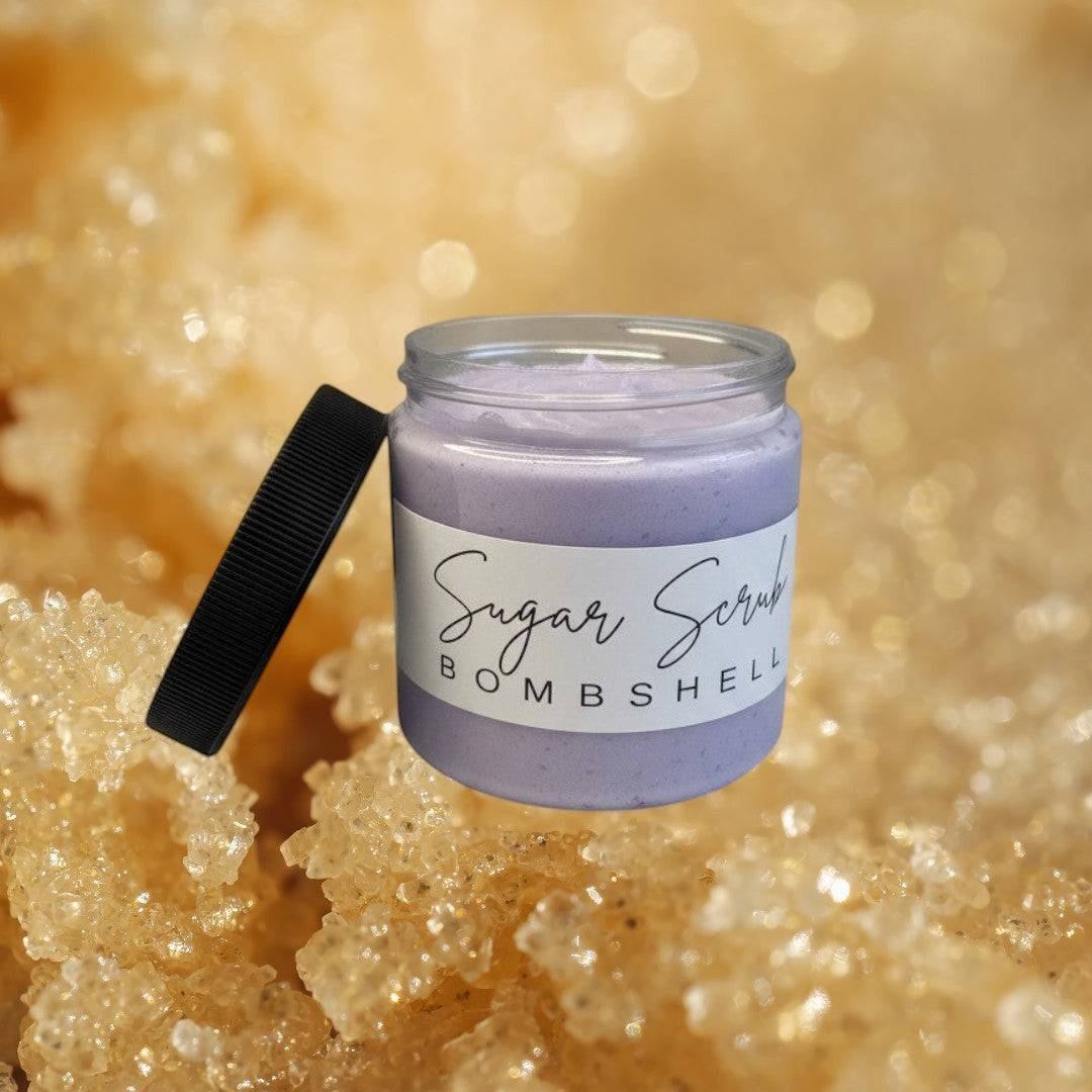 Doodlations Coffee Bar & Boutique Bombshell Sugar Scrub in a clear jar with a black lid. The scrub is a light purple color.
