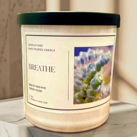 Doodlations hand-poured soy wax candle labeled "Breathe" with a botanical image, promoting relaxation.