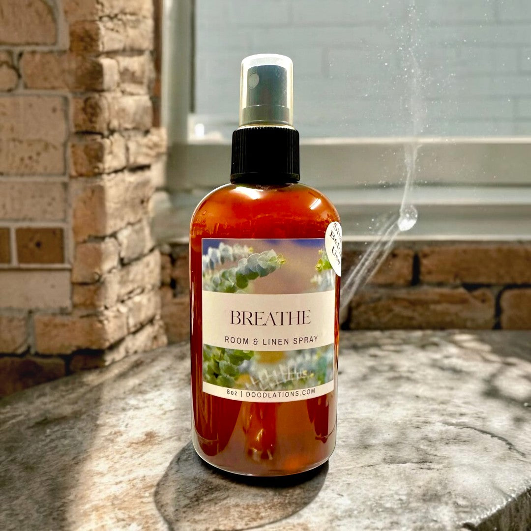 Doodlations Coffee Bar & Boutique Breathe Room & Linen Spray with eucalyptus, bergamot, and spearmint scent in amber bottle.