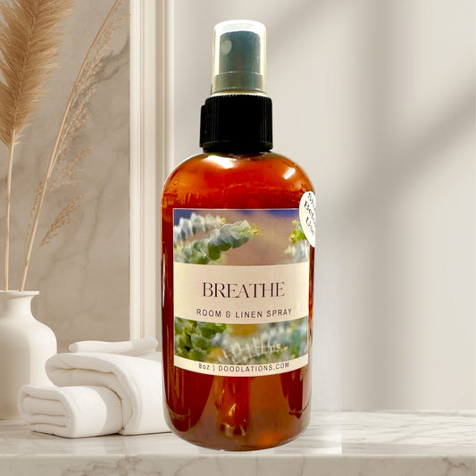 Doodlations Coffee Bar & Boutique Breathe room and linen spray with eucalyptus, bergamot, and spearmint scent in amber bottle.