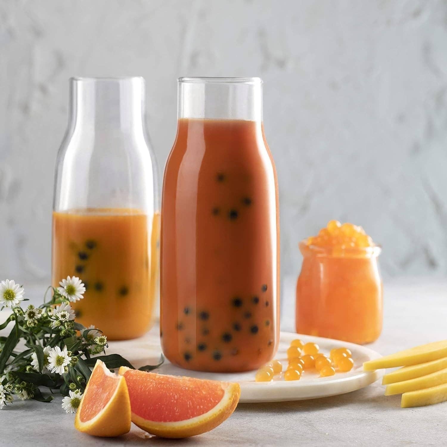 Doodlations Coffee Bar & Boutique Bursting Mango Balls in a drink and small jar, with grapefruit slices and mango strips.