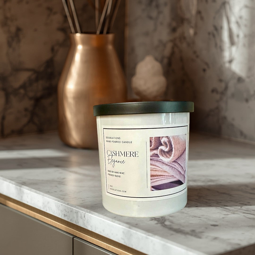 Doodlations Cashmere Elegance hand-poured parasoy blend candle with notes of amber, sugar, vanilla, plum, and cherry.