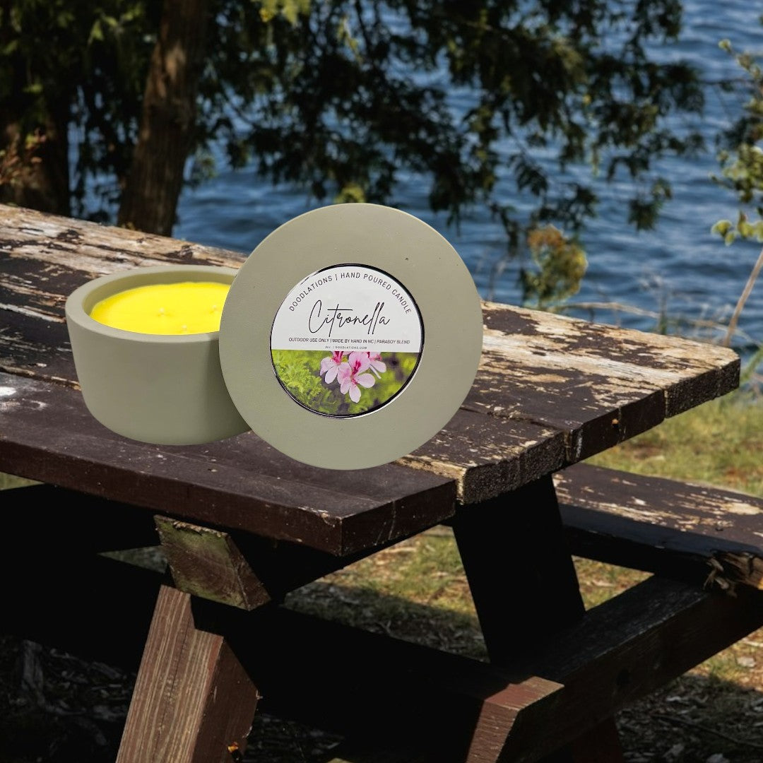 Doodlations 3-wick citronella candle in a grey concrete vessel with yellow wax. Features a label with pink flowers.