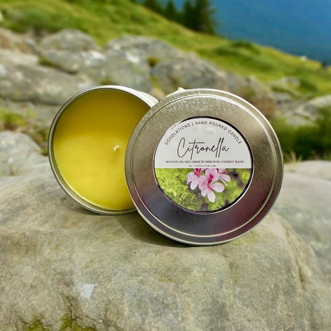 Doodlations Citronella outdoor candle in a metal tin with a yellow wax fill. Features a label with pink flowers.