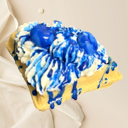 Doodlations Coffee Bar & Boutique Blueberry Waffle wax melt shaped like a waffle with whipped cream and blue syrup drizzle.