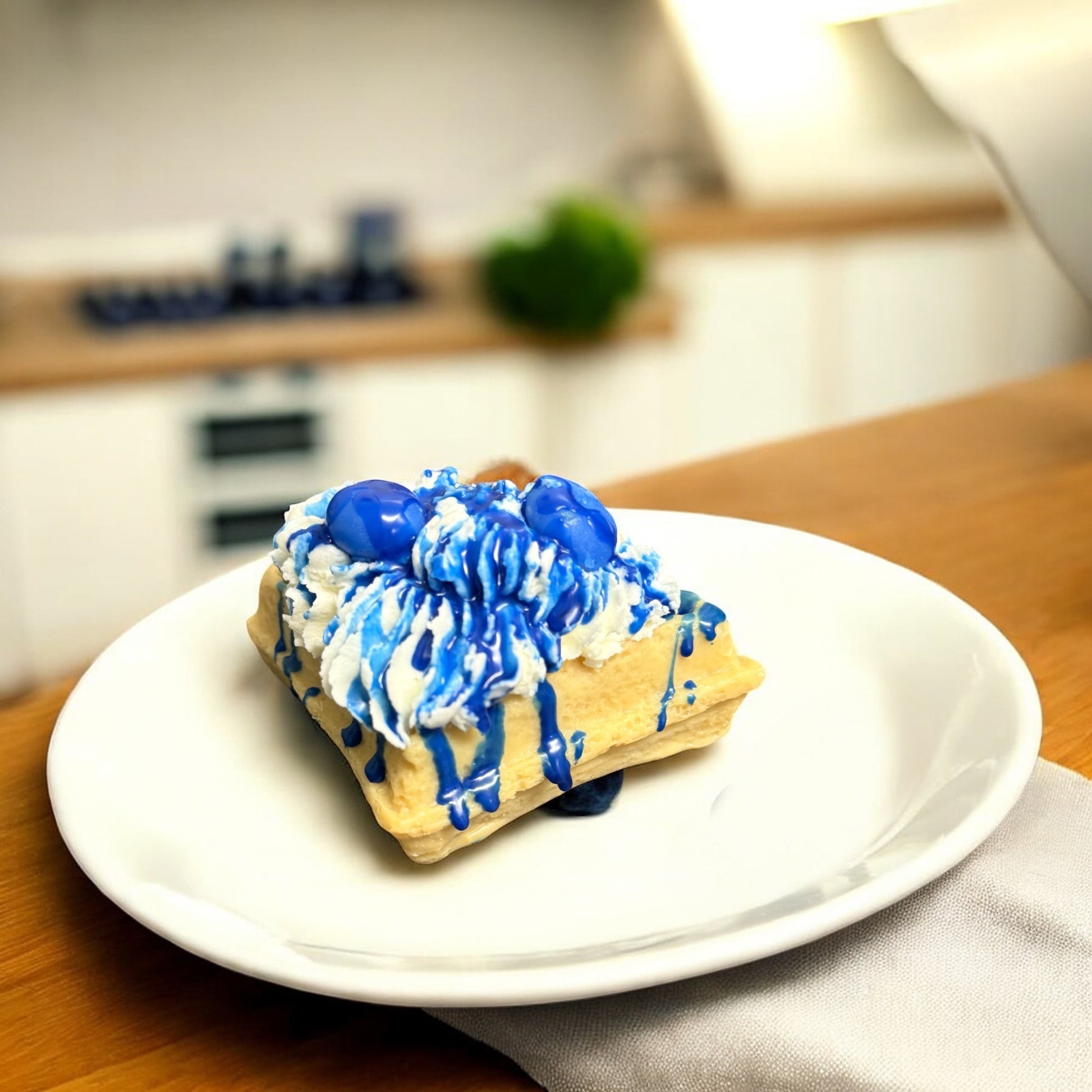 Doodlations Coffee Bar & Boutique Blueberry Waffle wax melt, shaped like a waffle with whipped cream and blue syrup.