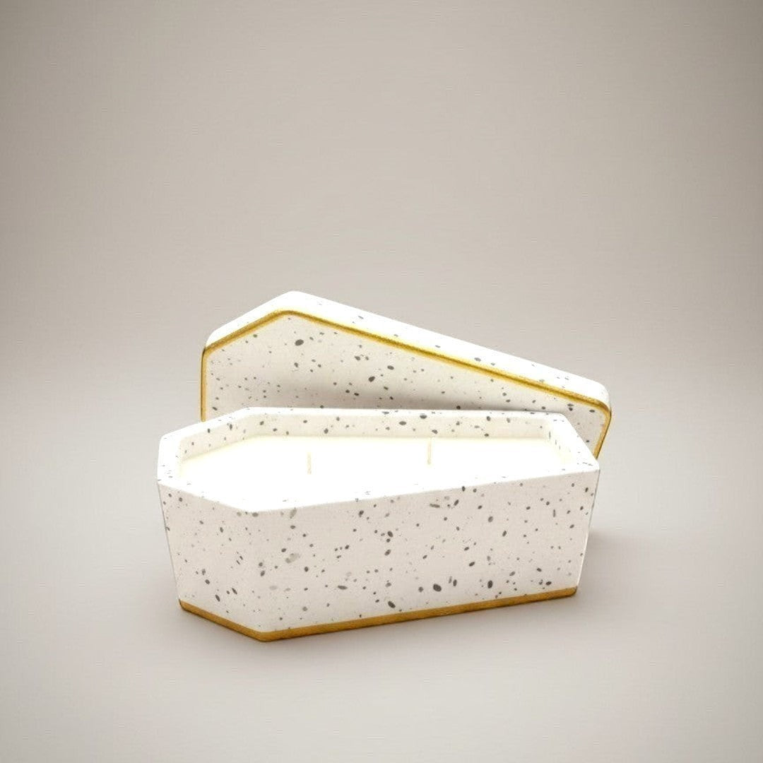 Doodlations Coffee Bar & Boutique Casket Concrete Candle with two wicks, made with soy blend wax in a speckled white concrete vessel with gold trim.