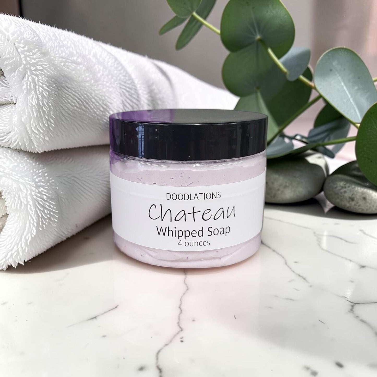 Doodlations Coffee Bar & Boutique Chateau whipped soap in a 4oz jar with a purple loofah on a marble surface.