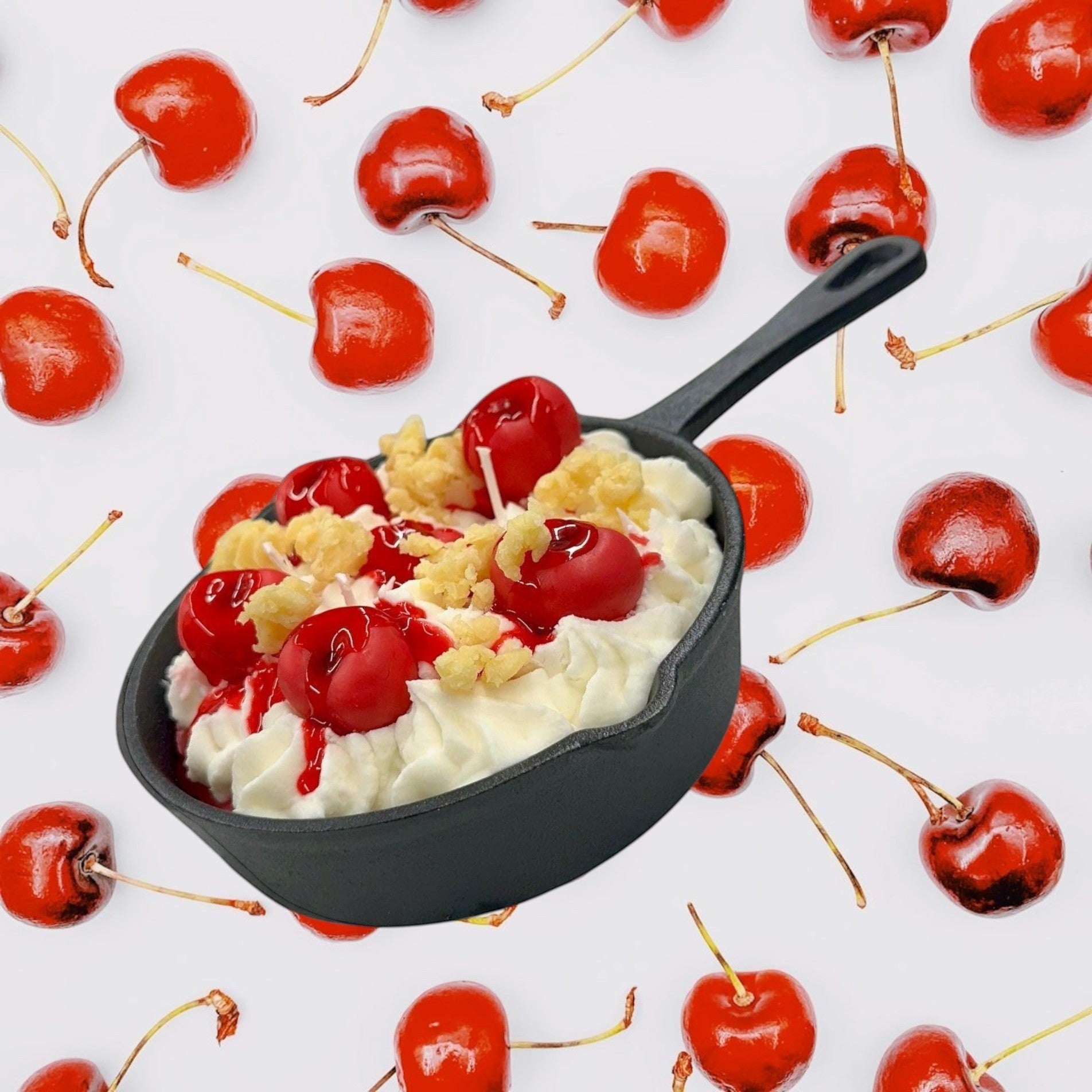 Doodlations Coffee Bar & Boutique Cherry Yum Yum candle in a black iron skillet with white wax frosting, red wax cherries, and crumble topping.