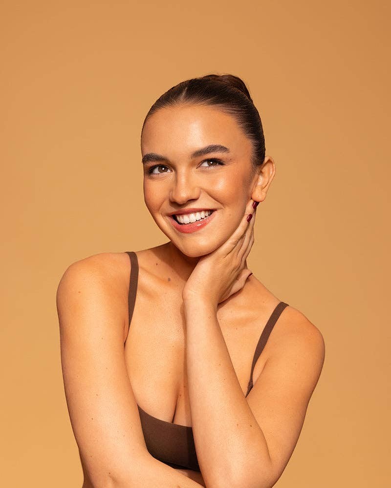 Smiling woman with a radiant sun-kissed glow using Doodlations Coffee Bar & Boutique Petajane Gradual Face Tan.