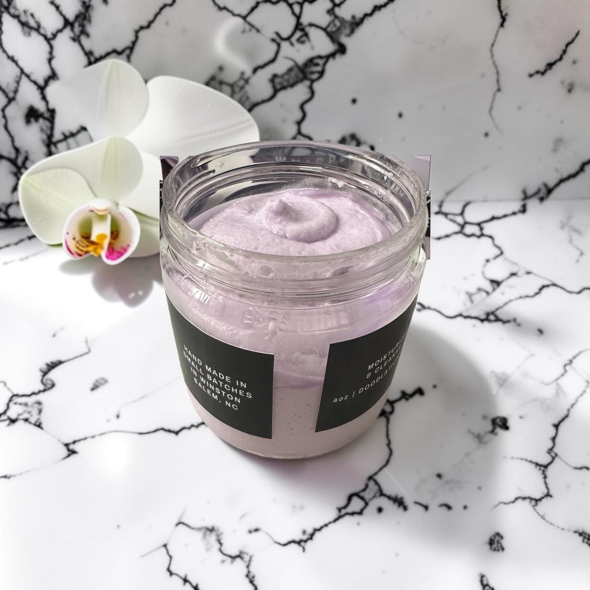 Doodlations Coffee Bar & Boutique Lavender Oasis whipped soap in a 4 oz jar with a white orchid on marble background.