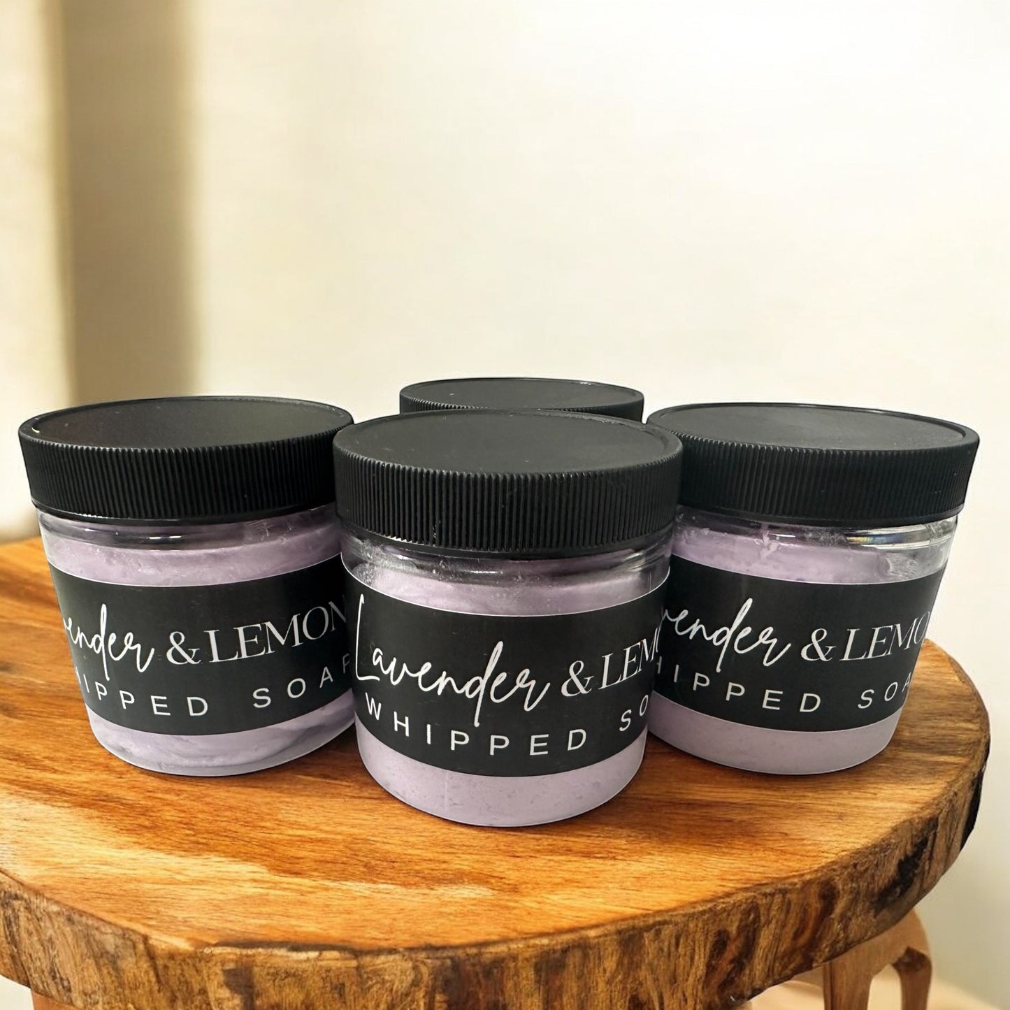 Doodlations Coffee Bar & Boutique Lavender Oasis whipped soap jars with black lids on a rustic wooden stand.