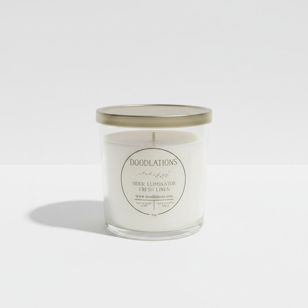 Doodlations Coffee Bar & Boutique Odor Eliminator candle in a clear glass jar with a gold lid and fresh linen scent.