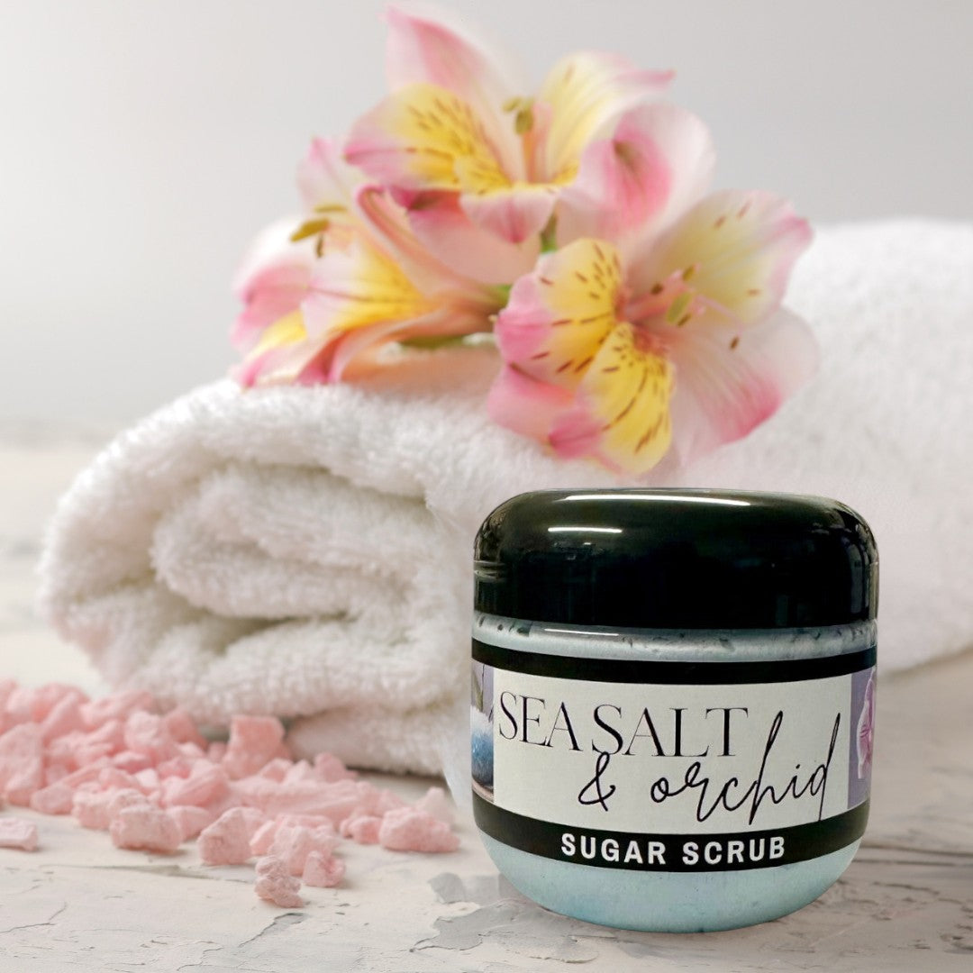 Doodlations Coffee Bar & Boutique Sea Salt & Orchid Sugar Scrub in a clear jar with a black lid, light blue scrub inside.