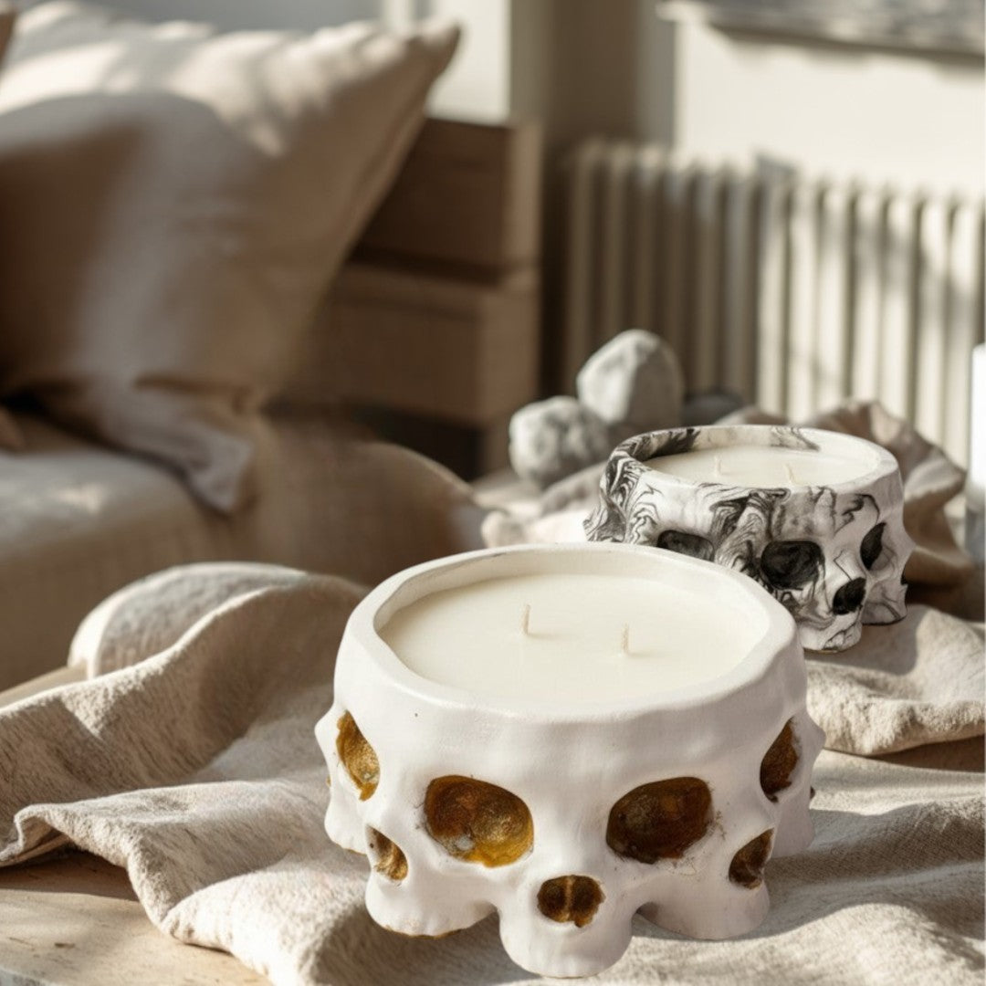 Doodlations Coffee Bar & Boutique white concrete skull candle with two wicks, and a marbled black and white skull candle behind it.