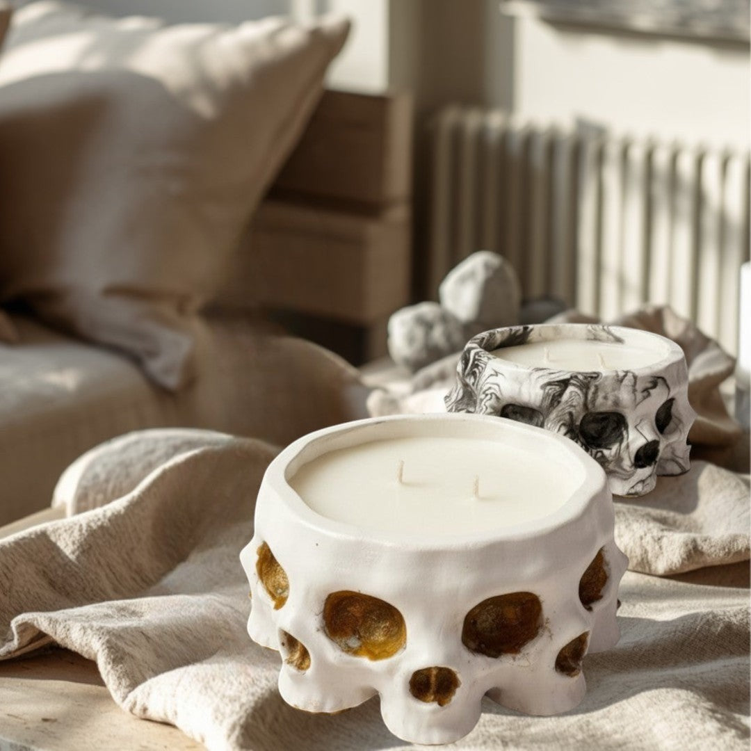 Doodlations Coffee Bar & Boutique white concrete skull candle with two wicks, and a marbled black and white skull candle behind it.