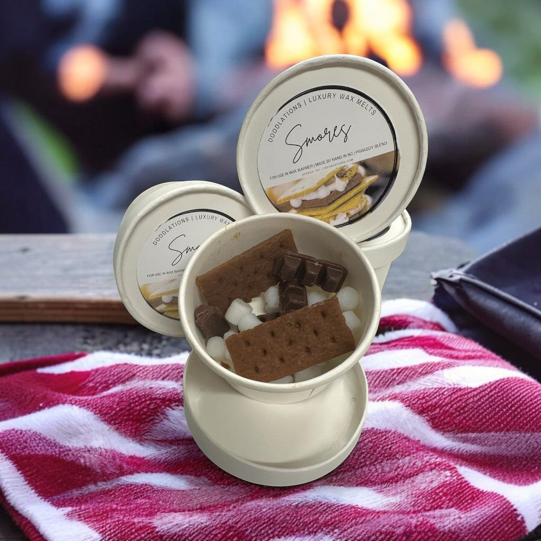 Doodlations Coffee Bar & Boutique Smores wax melts in a cup with graham crackers, chocolate, and marshmallows.