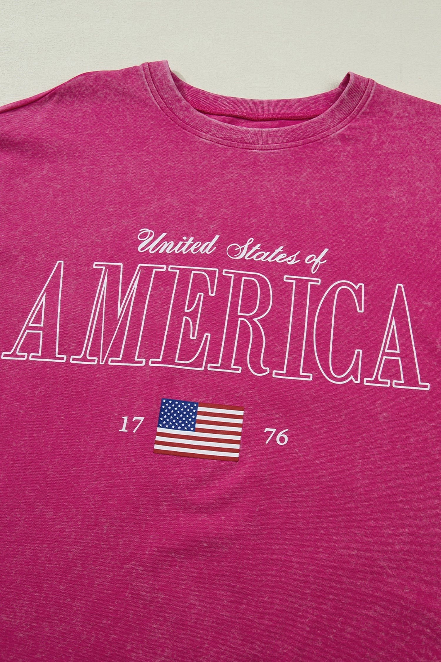 Doodlations Coffee Bar & Boutique AMERICA 1776 graphic tee in rose red mineral wash cotton with vintage lettering and US flag detail.