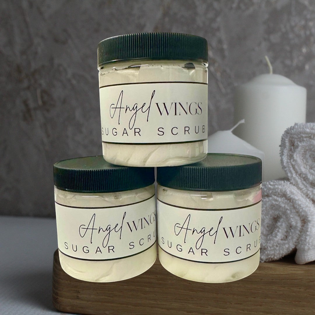 Doodlations Coffee Bar & Boutique Angel Wings sugar scrub in clear jars with black lids. Creamy white scrub with fine sugar crystals.