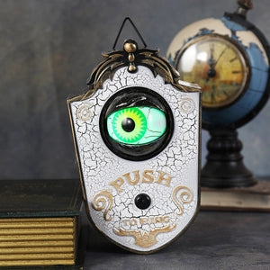 Doodlations Coffee Bar & Boutique animated Halloween doorbell with a glowing green eyeball in a vintage white shield