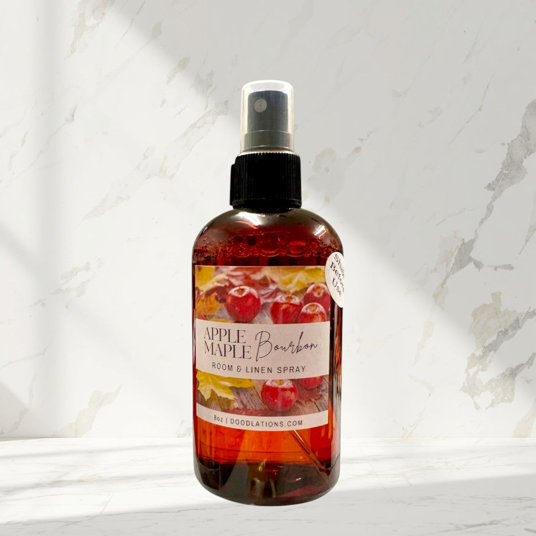 Doodlations Coffee Bar & Boutique Apple & Maple Bourbon room and linen spray in amber bottle with label featuring apples and autumn leaves.
