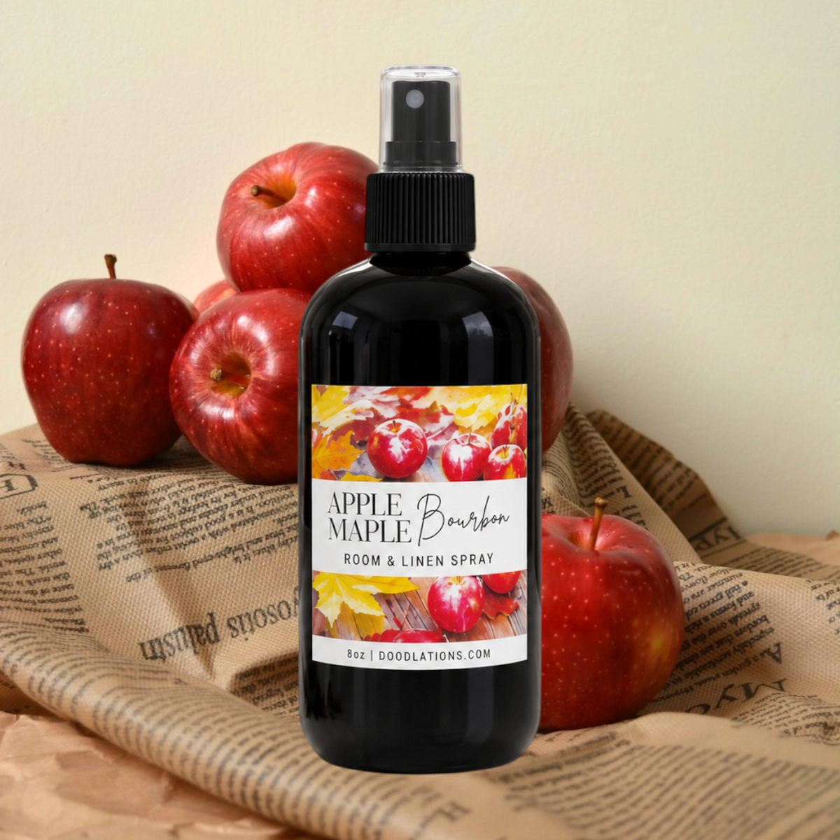 Doodlations Coffee Bar & Boutique Apple & Maple Bourbon room and linen spray in a black bottle with fresh red apples.