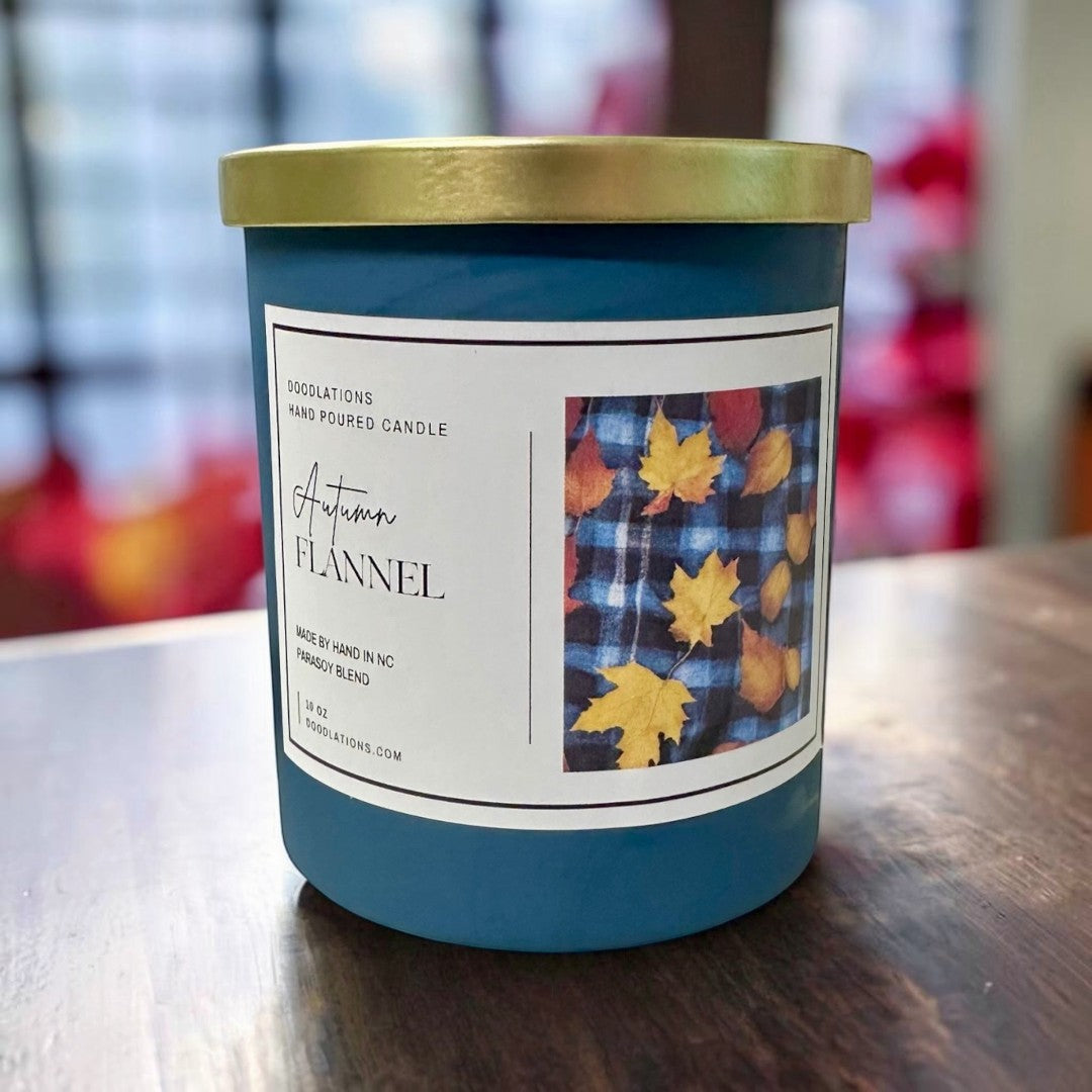 Doodlations Autumn Flannel luxury hand-poured soy blend candle in a teal jar with a gold lid, featuring a plaid and fall leaf label.