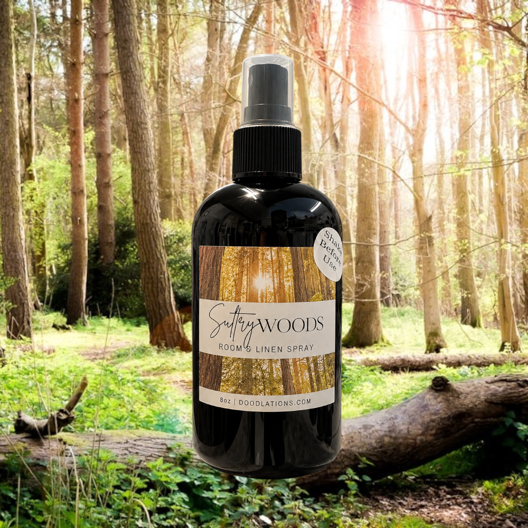 Doodlations Coffee Bar & Boutique Autumn Flannel room and linen spray in a black bottle against a forest background.