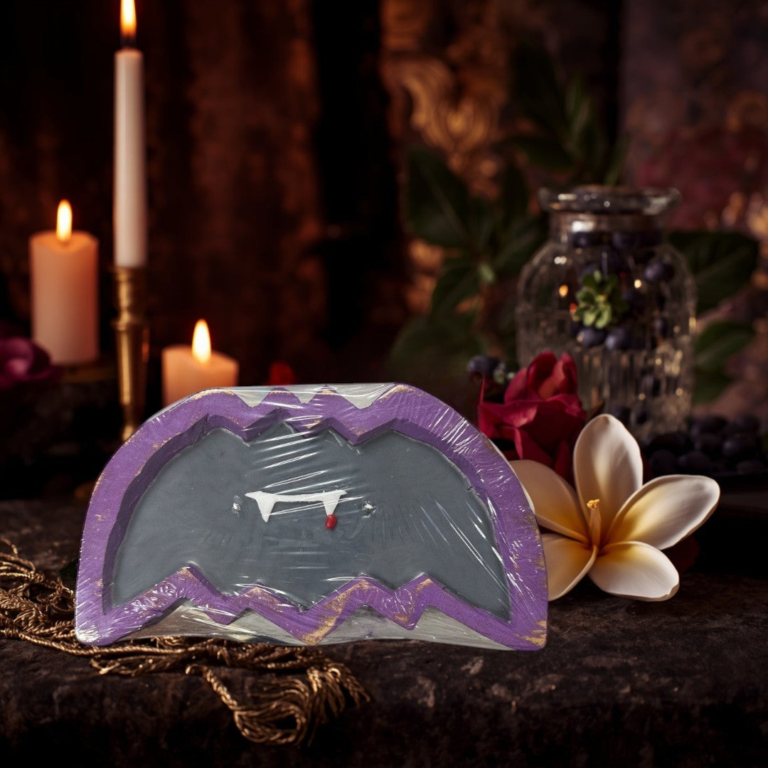 Doodlations Coffee Bar & Boutique Bat Dough Bowl Candle with fangs and a blood drop detail. Purple and gold trim.