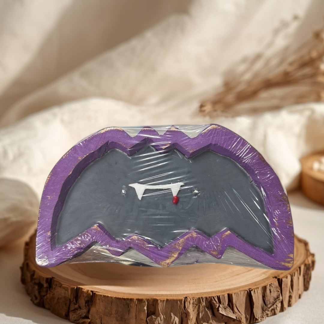 Doodlations Coffee Bar & Boutique Bat Dough Bowl Candle with fangs and a blood drop detail. Purple and gold trim.