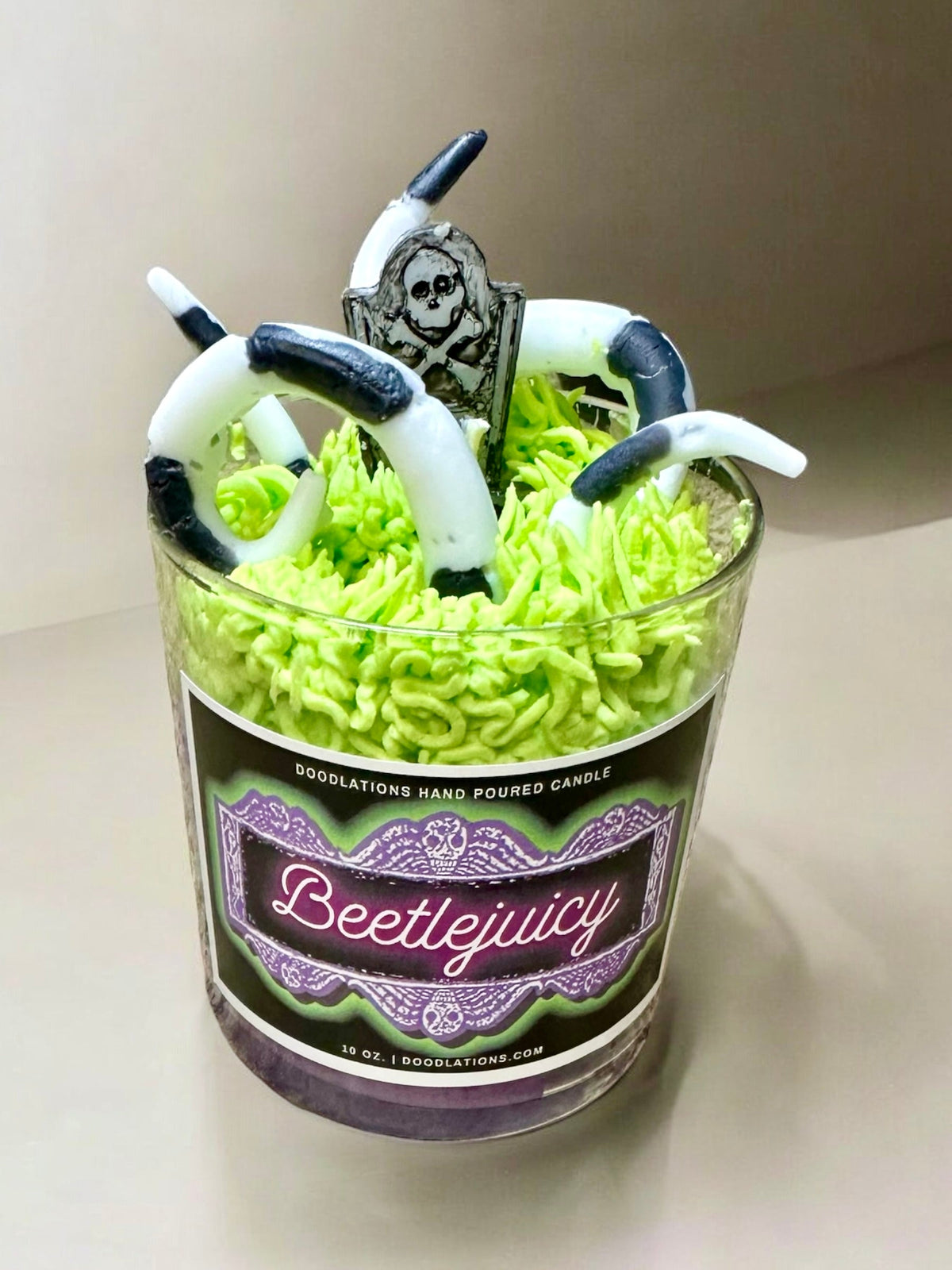 Doodlations Coffee Bar & Boutique Beetlejuicy luxury candle with green wax, sandworm details, and tombstone topper.