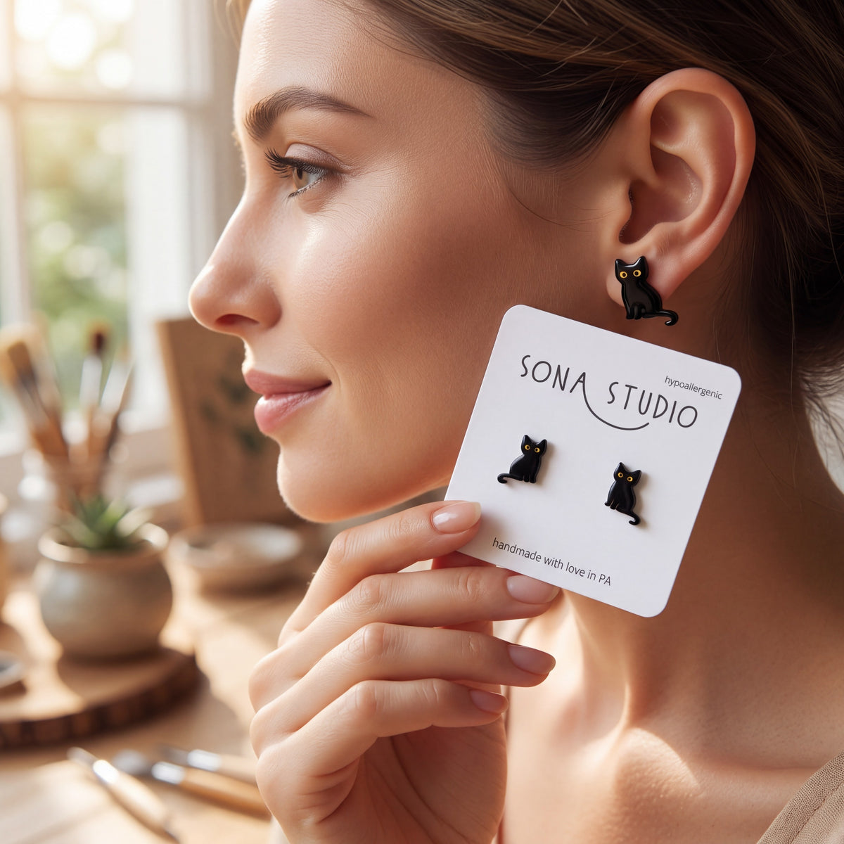 Doodlations Coffee Bar & Boutique black cat earrings with hypoallergenic stainless steel posts worn by a woman