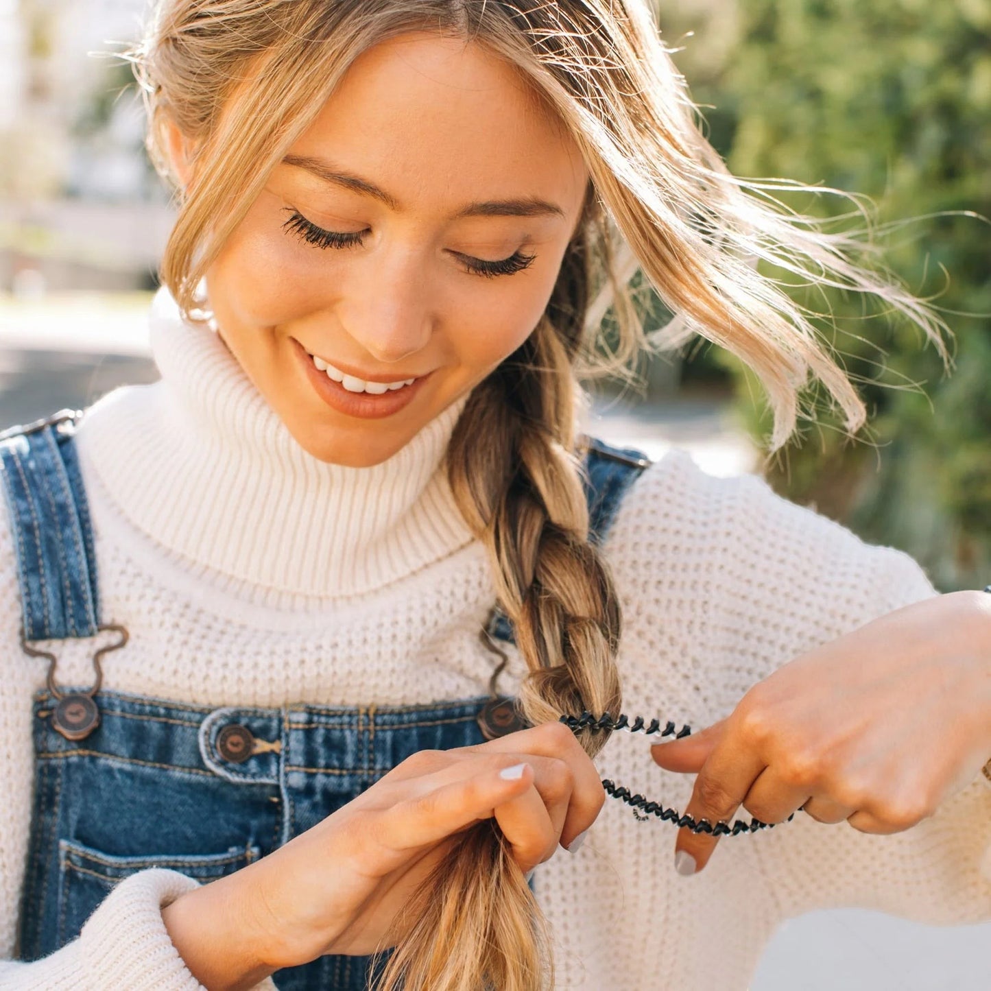 Doodlations Coffee Bar & Boutique jet black spiral hair tie securing a blonde braid on a woman in a white sweater