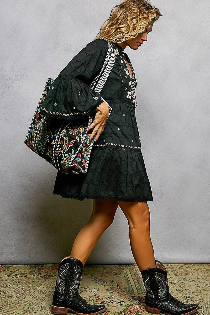 Doodlations Coffee Bar & Boutique black quilted tote bag with floral embroidery and striped binding carried by a model
