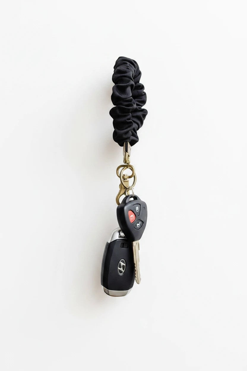 Doodlations Coffee Bar & Boutique black luxe satin scrunchie keychain with gold hardware and car keys attached