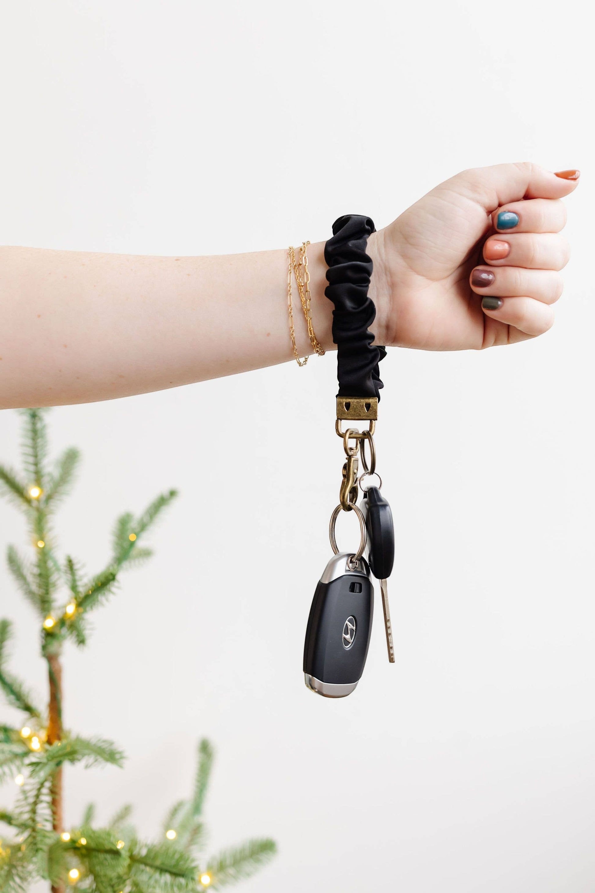 Doodlations Coffee Bar & Boutique black satin scrunchie keychain worn on a wrist with car keys