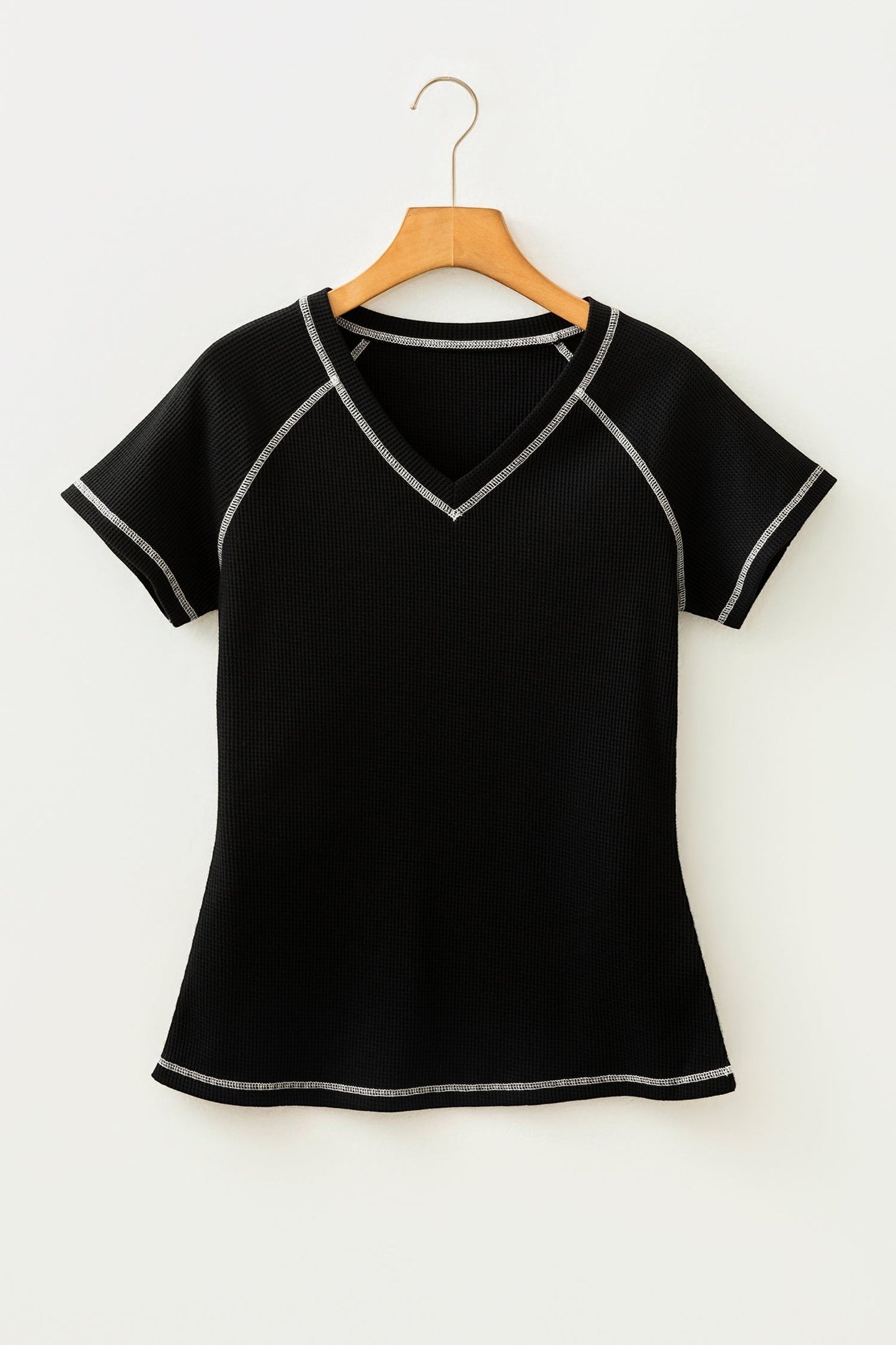Doodlations Coffee Bar & Boutique black waffle knit V-neck top with white contrast stitching on a wooden hanger
