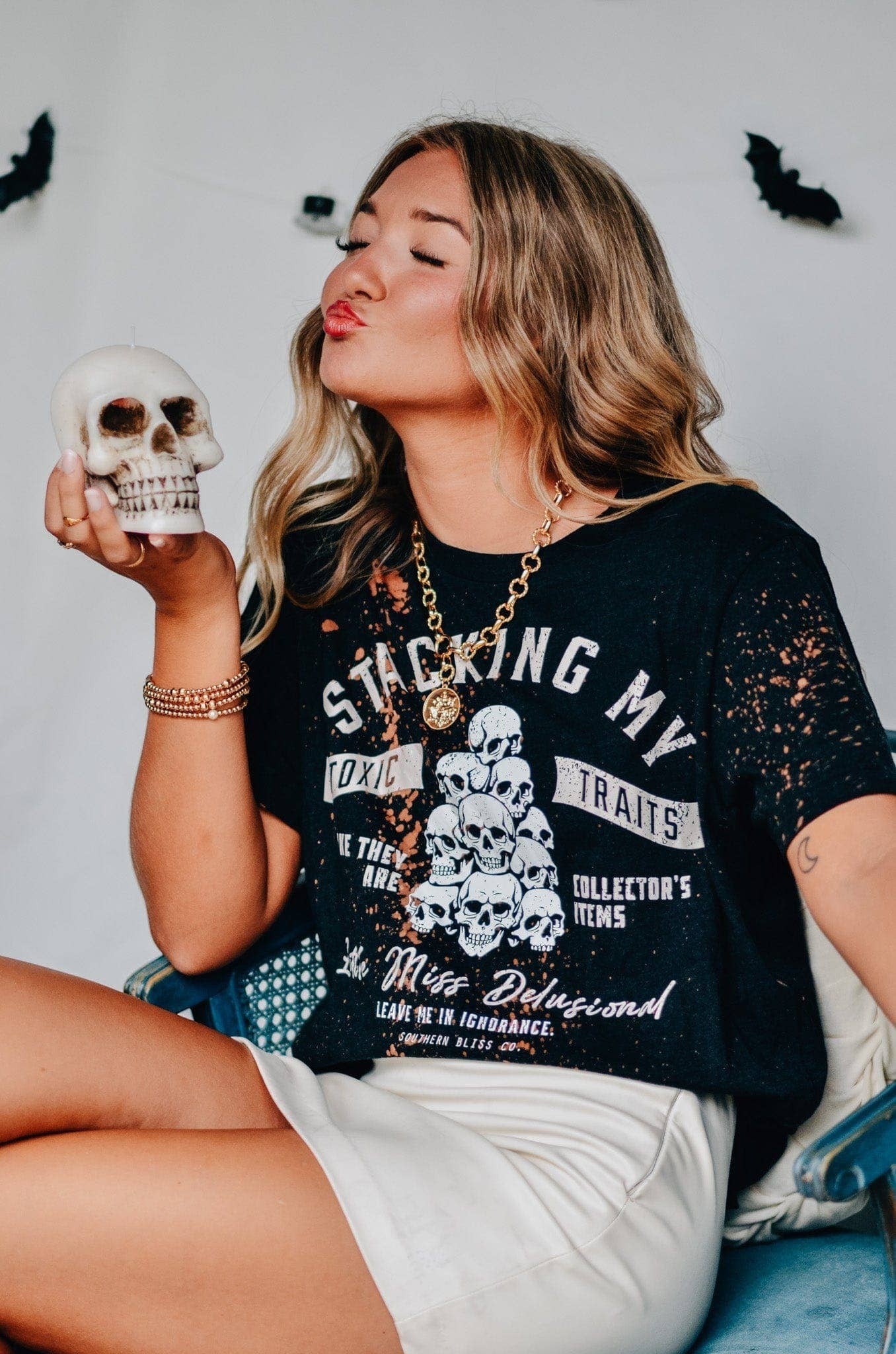 Doodlations Coffee Bar & Boutique black bleached graphic tee with skull print worn by a woman holding a skull prop