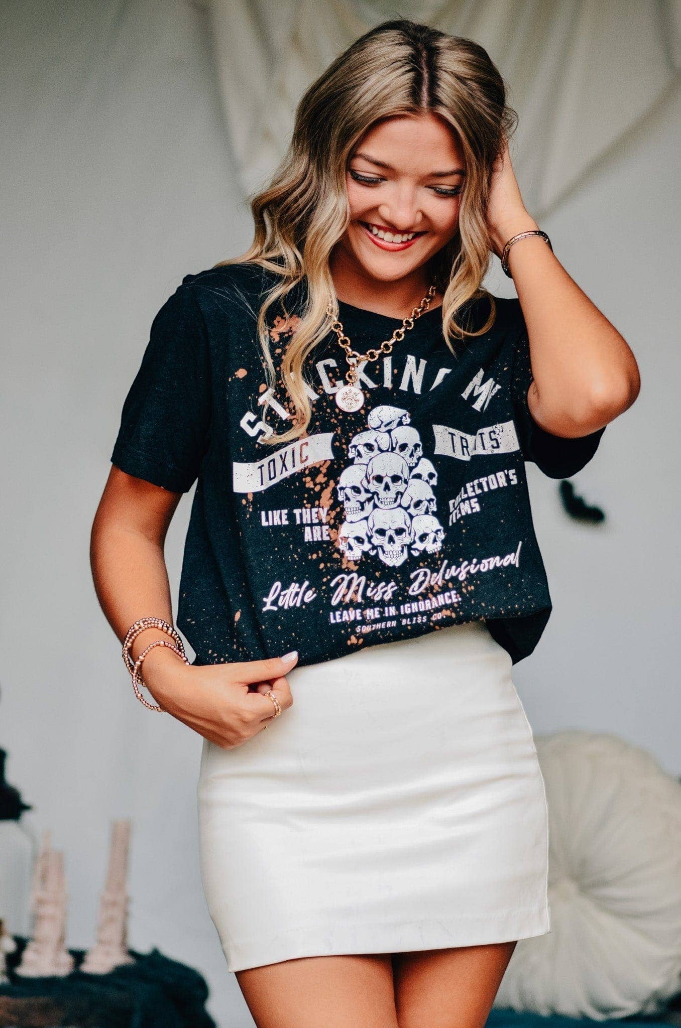 Doodlations Coffee Bar & Boutique black bleached graphic tee with skull print and sassy text worn by a smiling woman