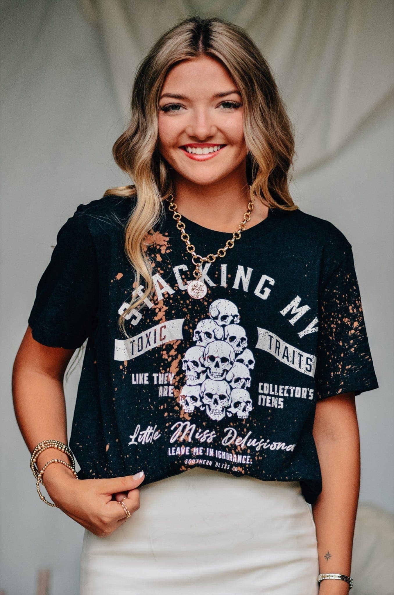 Doodlations Coffee Bar & Boutique black bleached t-shirt with skull graphic and sassy text worn by a smiling woman.